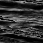 A serene black and white abstract capture of water waves creating fluid textures.