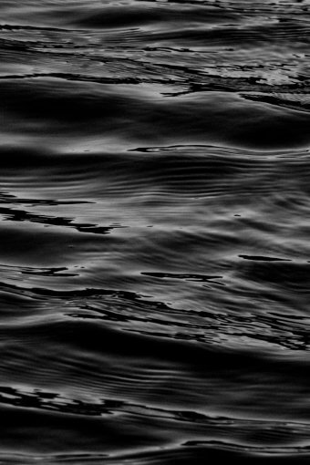 A serene black and white abstract capture of water waves creating fluid textures.