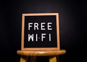 A wooden frame sign with 'Free Wi-Fi' text displayed on a stool in a dark room.