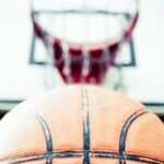 Vivid image of a basketball aiming for a hoop outdoors in daylight.