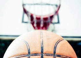 Vivid image of a basketball aiming for a hoop outdoors in daylight.