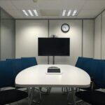 Sleek conference room with a table, chairs, TV, and video conferencing equipment.