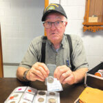 Carl E. Moore of Osgood, holds a Kennedy half dollar he will be giving away as a door prize at the Osgood Historical Museum this weekend.